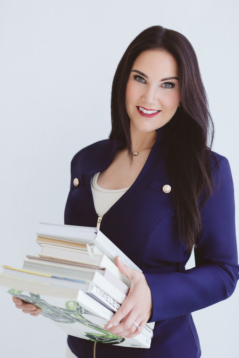 Victoria in a blue jacket holding a pile of books