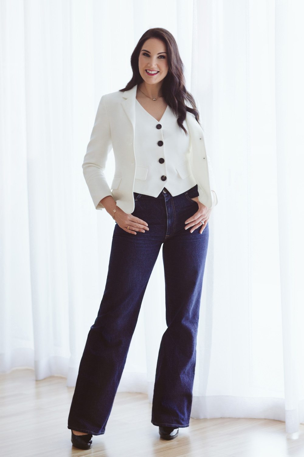 Victoria in a white jacket and blue trousers stood with her hands at her waist